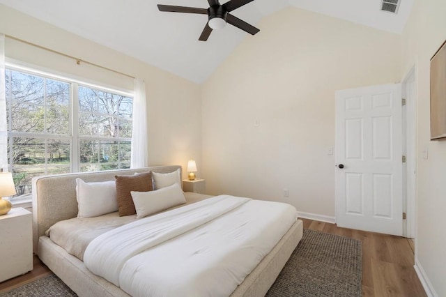 bedroom featuring high vaulted ceiling, wood finished floors, visible vents, and baseboards