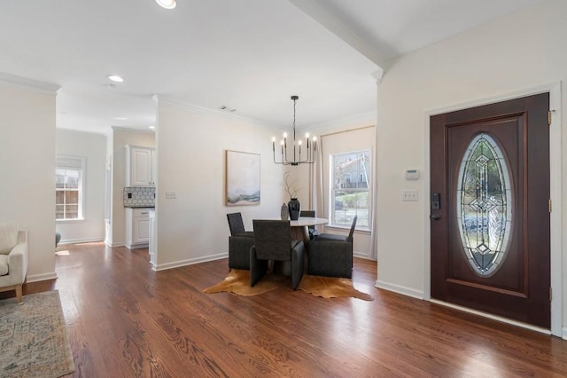 foyer entrance featuring dark wood-style floors, a chandelier, baseboards, and ornamental molding