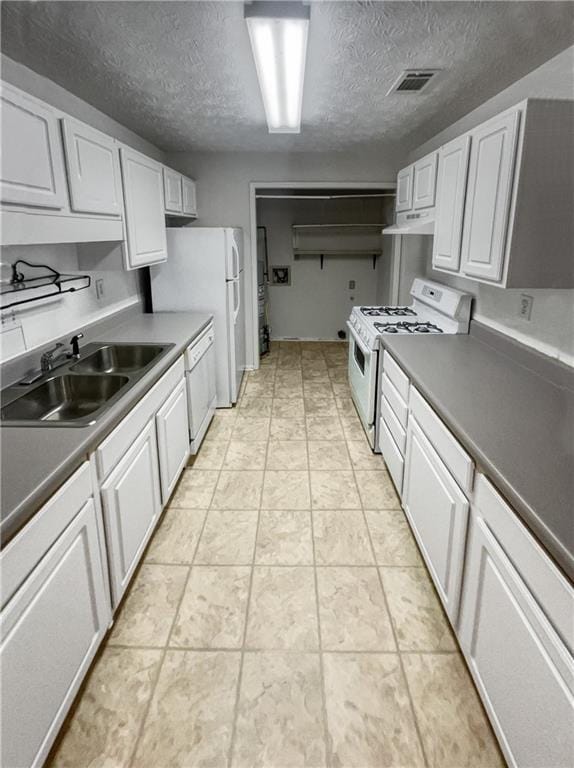 kitchen featuring white appliances, white cabinets, a textured ceiling, and sink