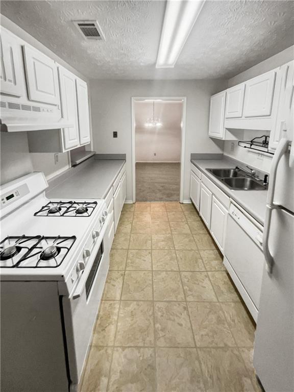 kitchen with white appliances, a textured ceiling, light colored carpet, white cabinetry, and sink