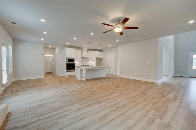 unfurnished living room featuring ceiling fan and light hardwood / wood-style floors