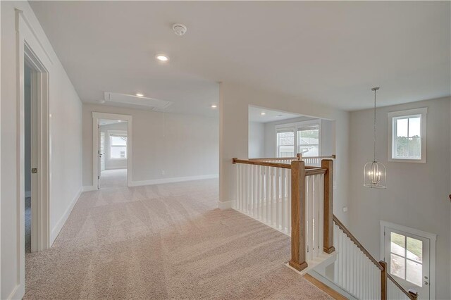 hall with a healthy amount of sunlight and light colored carpet