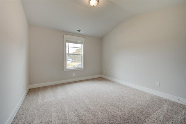 carpeted empty room featuring vaulted ceiling