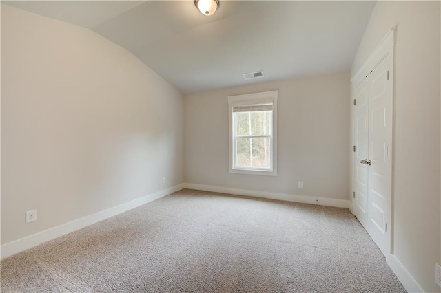 unfurnished room with carpet and vaulted ceiling