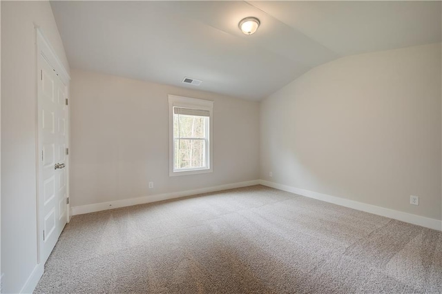 carpeted spare room featuring vaulted ceiling