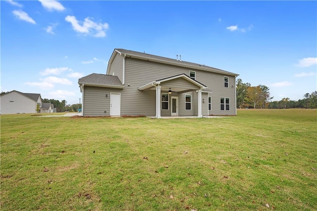 back of property with a yard and ceiling fan