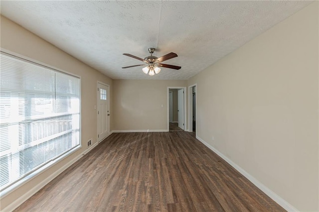 empty room with a textured ceiling, dark hardwood / wood-style flooring, and ceiling fan