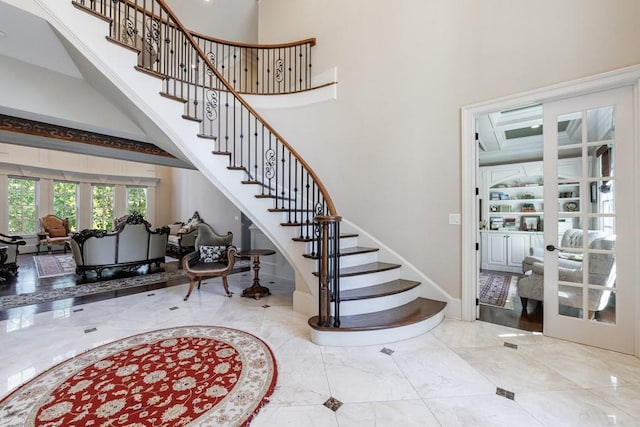 stairs featuring a towering ceiling and french doors