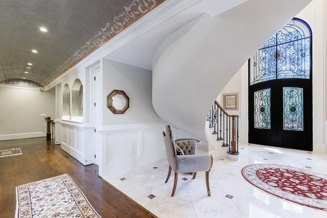 entrance foyer with hardwood / wood-style flooring, crown molding, and french doors