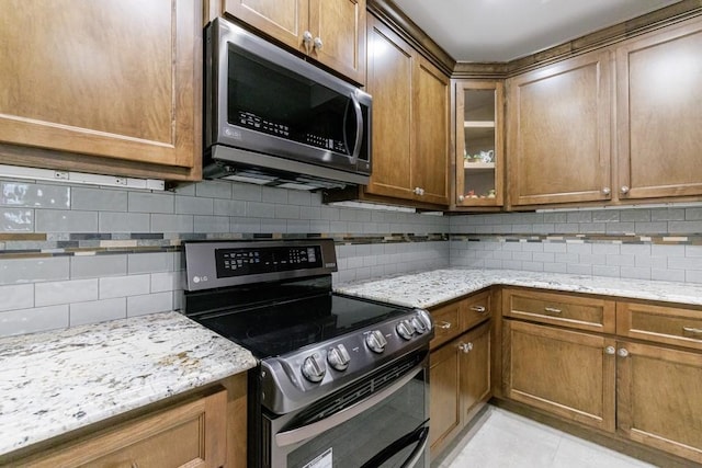 kitchen featuring light stone countertops, black range with electric cooktop, backsplash, and light tile patterned floors