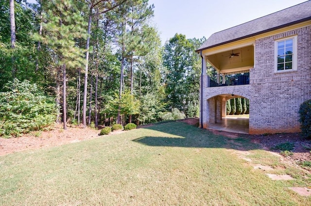 view of yard featuring a balcony, a patio area, and ceiling fan