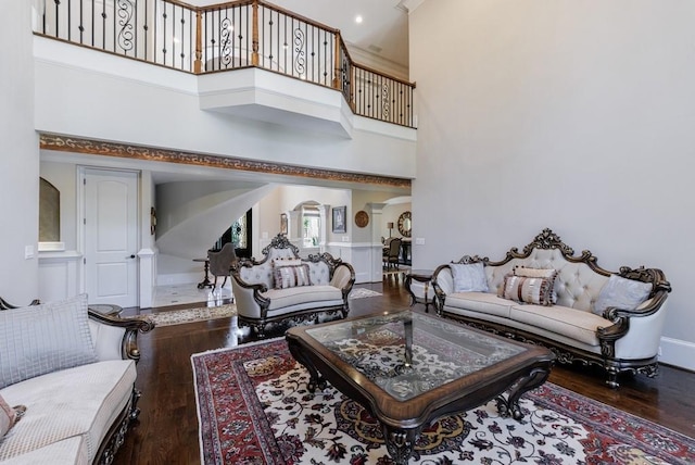 living room featuring a towering ceiling and dark hardwood / wood-style flooring