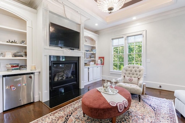 living room featuring crown molding, built in shelves, and dark hardwood / wood-style floors