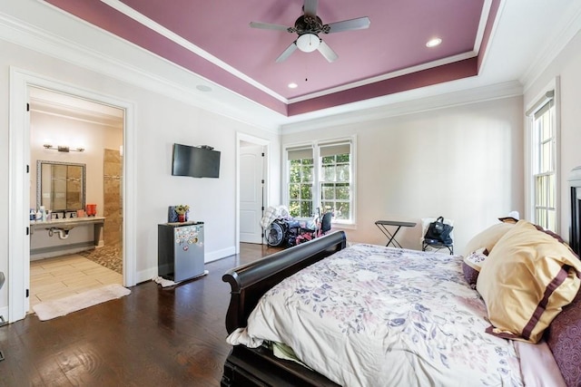 bedroom featuring ceiling fan, a raised ceiling, dark hardwood / wood-style floors, crown molding, and ensuite bathroom