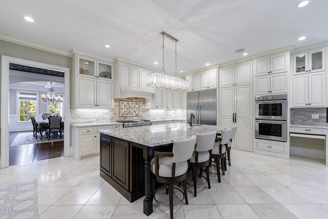 kitchen featuring stainless steel appliances, crown molding, a center island with sink, and decorative backsplash