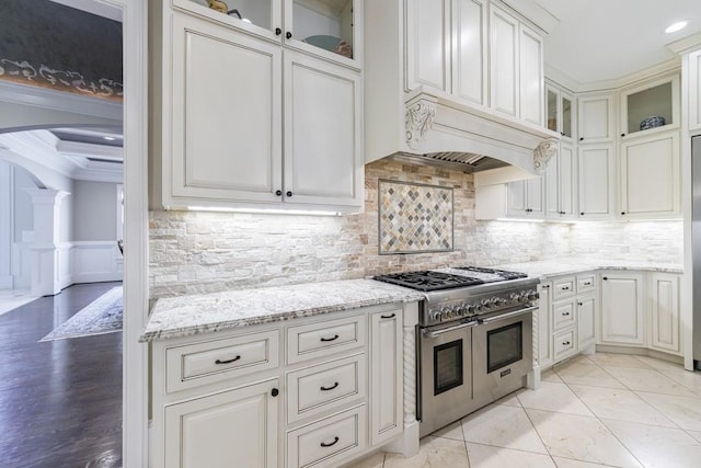 kitchen with light stone counters, crown molding, white cabinetry, double oven range, and backsplash