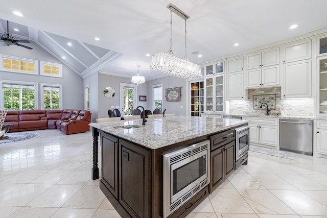 kitchen with dark brown cabinetry, decorative light fixtures, sink, an island with sink, and appliances with stainless steel finishes