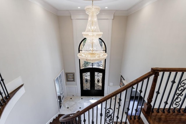 foyer featuring french doors, an inviting chandelier, and crown molding