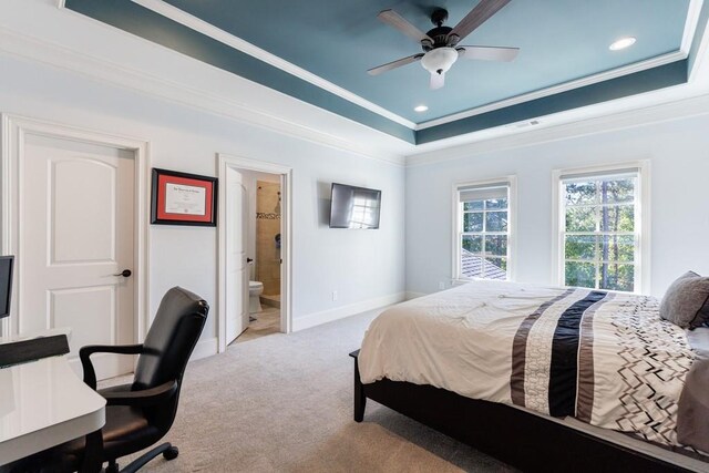 bedroom featuring ceiling fan, a raised ceiling, crown molding, light carpet, and ensuite bath