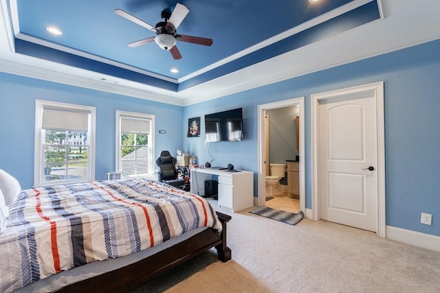 bedroom with ensuite bathroom, ceiling fan, light carpet, and a raised ceiling