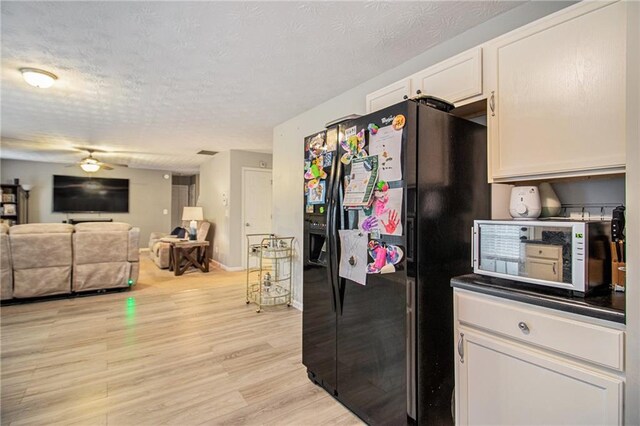 kitchen with black fridge with ice dispenser, a textured ceiling, ceiling fan, light hardwood / wood-style floors, and white cabinetry