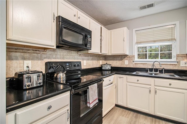 kitchen with sink, light hardwood / wood-style flooring, a textured ceiling, white cabinets, and black appliances