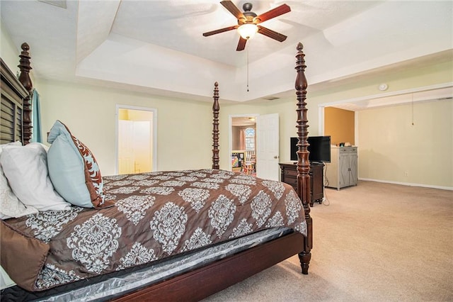 carpeted bedroom with a raised ceiling and ceiling fan