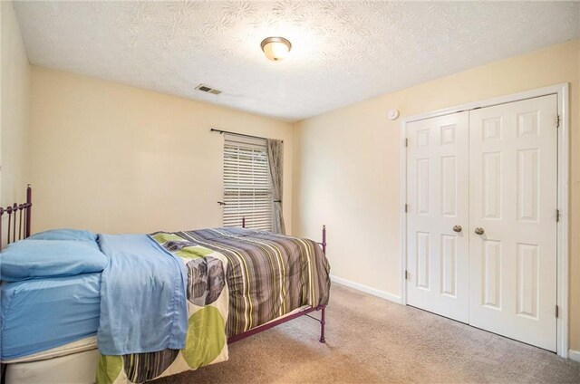 bedroom featuring carpet floors, a textured ceiling, and a closet