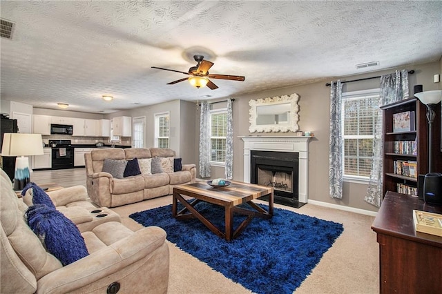 living room featuring a textured ceiling, light colored carpet, and a healthy amount of sunlight