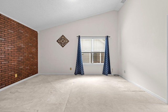 spare room featuring lofted ceiling, light colored carpet, a textured ceiling, and brick wall