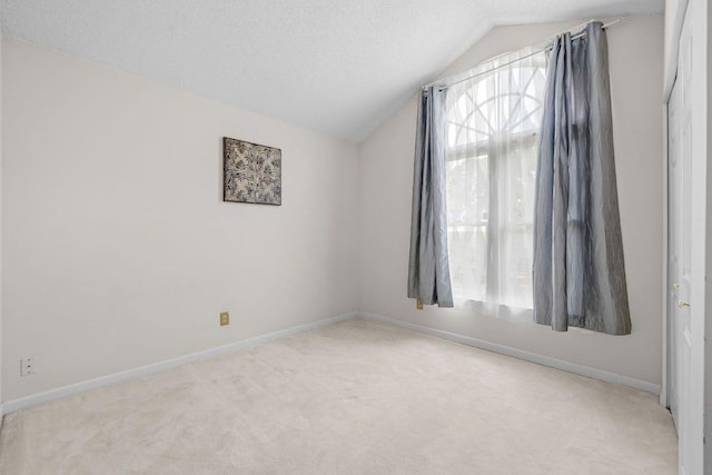 carpeted empty room with lofted ceiling and a textured ceiling