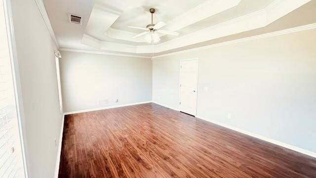 spare room with baseboards, a raised ceiling, a ceiling fan, dark wood-style flooring, and crown molding