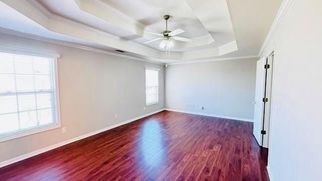 unfurnished room with dark wood-type flooring, a raised ceiling, a wealth of natural light, and crown molding