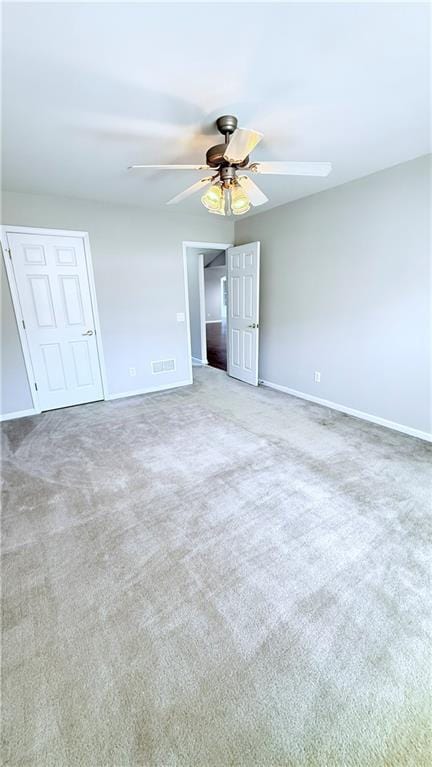 unfurnished bedroom featuring a ceiling fan, light colored carpet, and baseboards