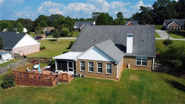 rear view of property featuring a deck, a chimney, a fenced backyard, and a sunroom