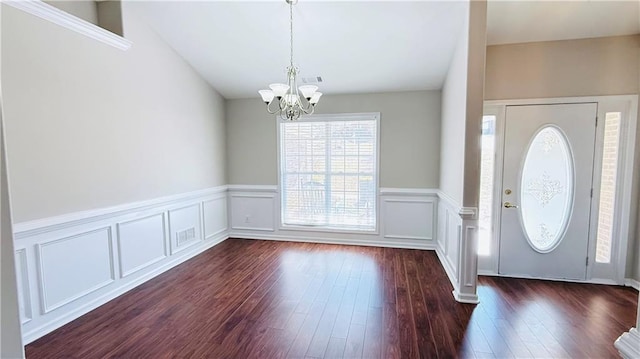 foyer entrance featuring visible vents, wainscoting, dark wood-style floors, an inviting chandelier, and a decorative wall