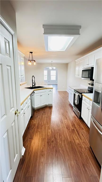 kitchen with stainless steel appliances, white cabinets, and pendant lighting