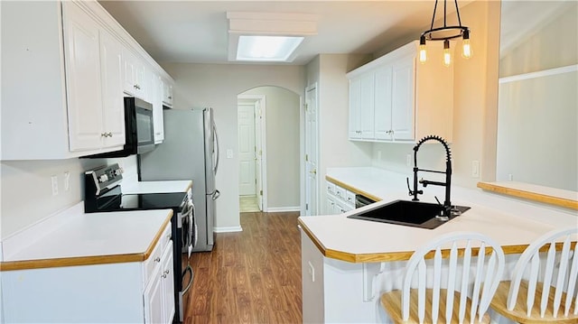 kitchen featuring electric stove, decorative light fixtures, a peninsula, white cabinetry, and a sink