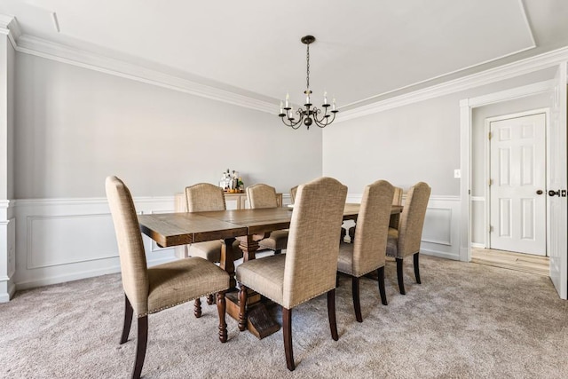 dining room featuring ornamental molding, light carpet, an inviting chandelier, and a decorative wall