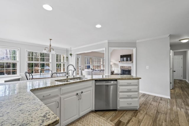 kitchen featuring stainless steel dishwasher, ornamental molding, a sink, white cabinets, and light wood-type flooring
