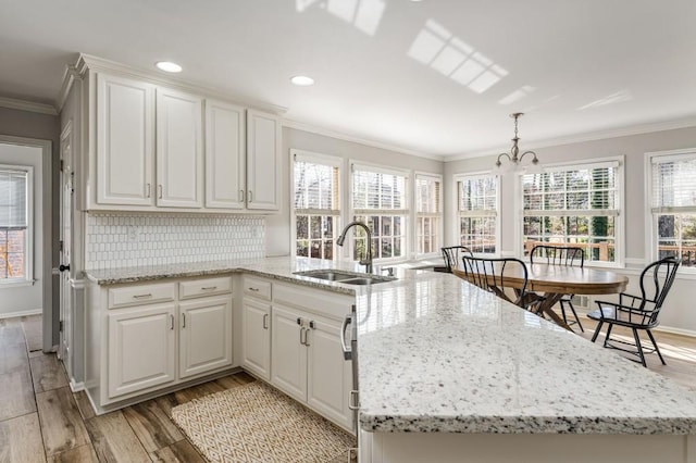 kitchen featuring a notable chandelier, light wood-style flooring, crown molding, and a sink