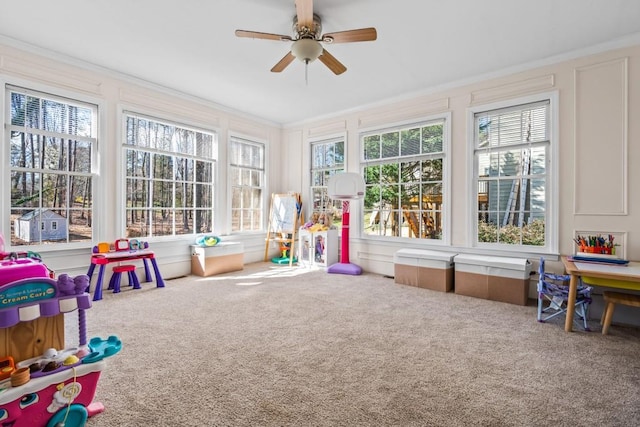 game room with crown molding, a wealth of natural light, carpet floors, and ceiling fan