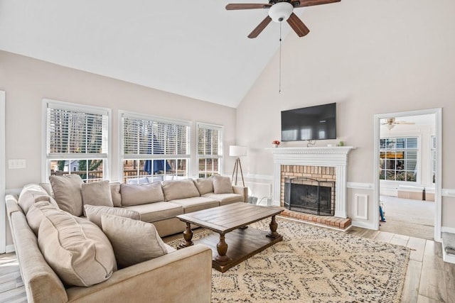 living room with high vaulted ceiling, a brick fireplace, a ceiling fan, and wood finished floors