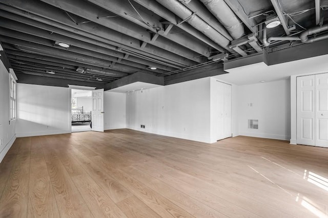 finished below grade area featuring baseboards, visible vents, and wood finished floors