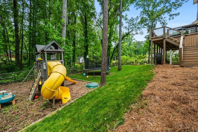 view of jungle gym with a trampoline, fence, a lawn, a deck, and stairway