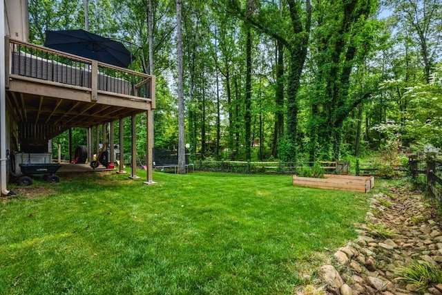 view of yard with a fenced backyard, a vegetable garden, a wooden deck, and a trampoline