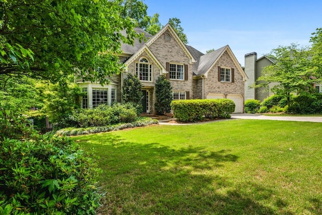 view of front of property featuring driveway, brick siding, an attached garage, stone siding, and a front lawn