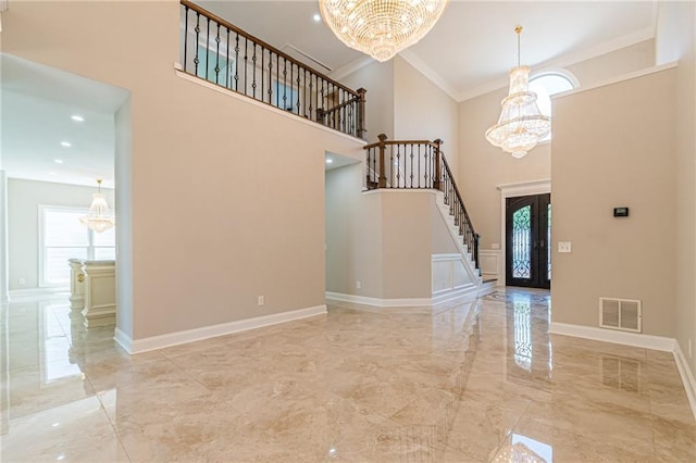 entryway with french doors, a high ceiling, crown molding, and a notable chandelier