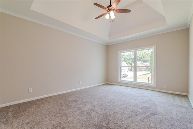 carpeted empty room with a raised ceiling, ceiling fan, and crown molding