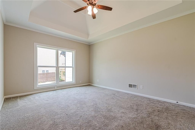 carpeted spare room featuring ceiling fan, a raised ceiling, and ornamental molding